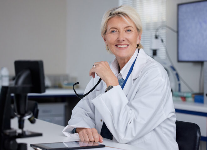 Smiling doctor with stethoscope at desk