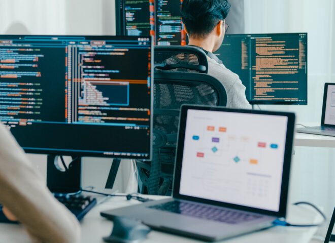Software developers coding at multi-monitor workstation