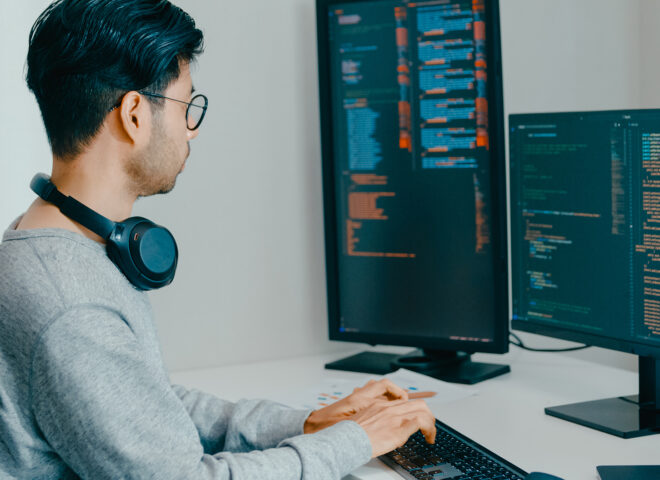 Software developer coding at dual-monitor workstation